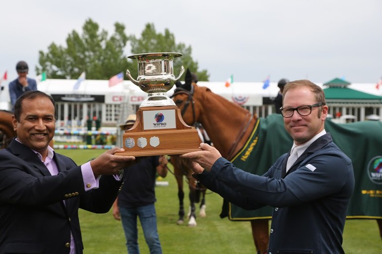 Ray Texel hoists the champions trophy with Devasis Nayak, Managing Director at Wipro Canada. Photo (c) Spruce Meadows Media Services. 