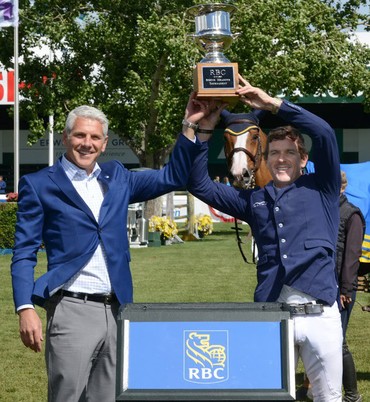 Conor Swail (IRL) hoists the champions trophy with Jeff Boyd, Regional President Alberta and Territories, RBC Royal Bank. Photo (c) Spruce Meadows Media Services.