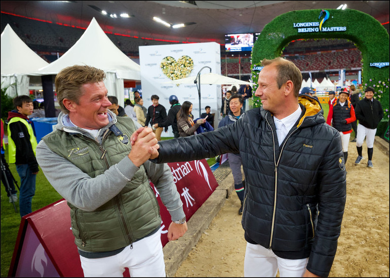 Jeroen Dubbeldam congratulates Marco Kutscher for his victory in the team jumping competition. Photo (c) Longines Equestrian Beijing Masters/Arnd Bronkhorst.