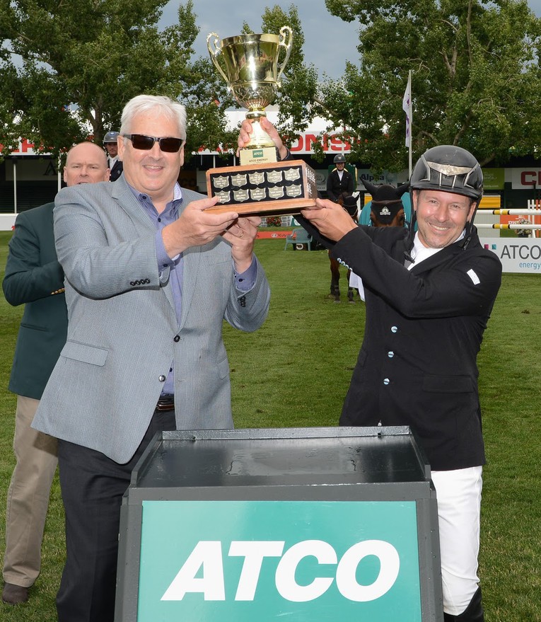 Eric Lamaze CAN hoists the Champions trophy with Pat Creaghan, President, ATCO Energy. Photo (c) Spruce Meadows Media Services.